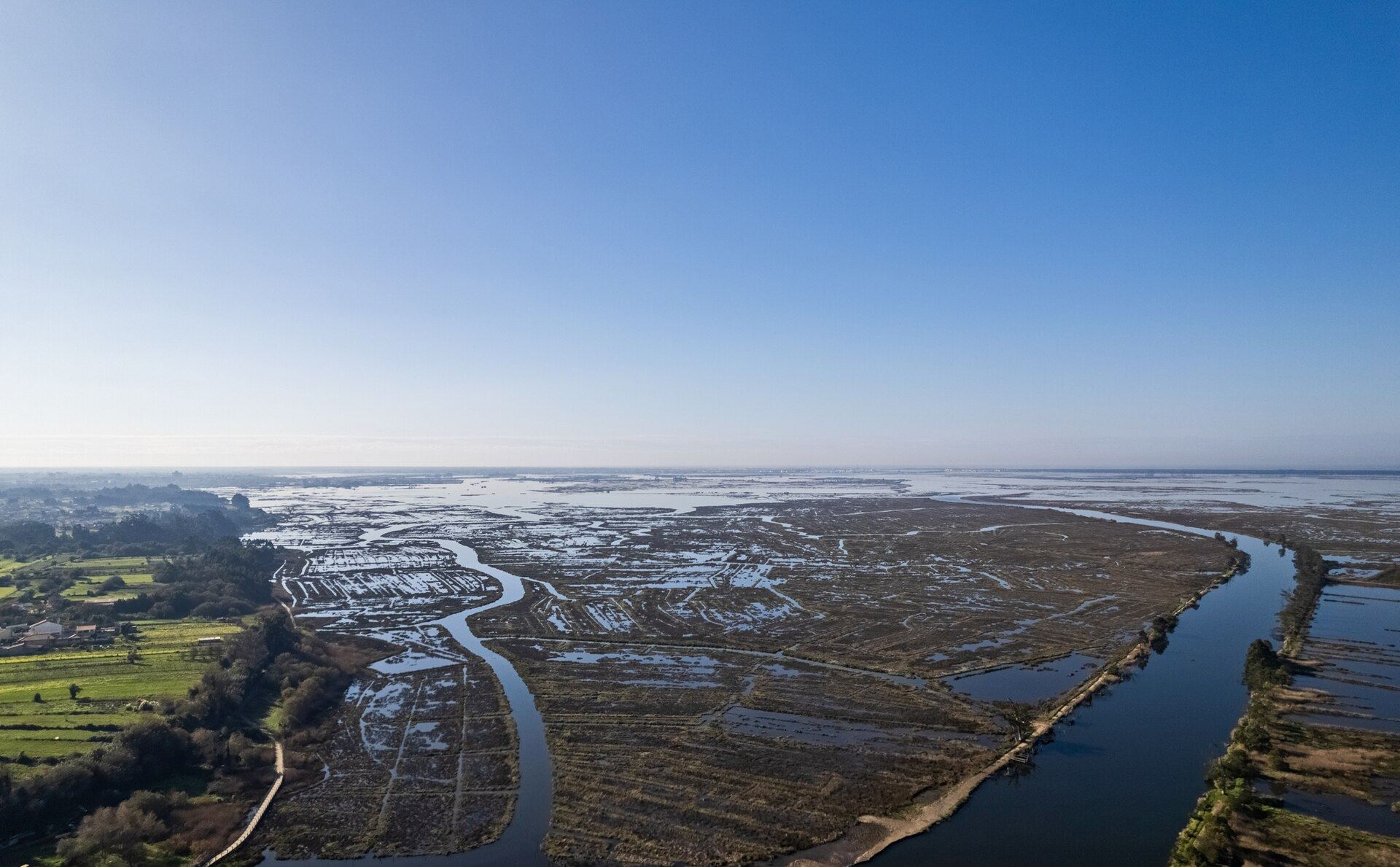 Aerial view of the Ria de Aveiro: salt pans and channels running out towards the sea under a clear sky